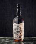 A bottle of Rusty Juggler Black Spiced Rum stands on a glass table.