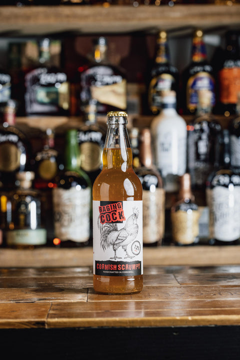 'Cornish O'cock Craft Cider' against a dark, rustic wooden table background.