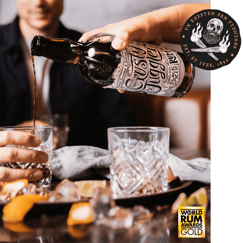 A hand holds a bottle of Susa Straight Rum over a glass, pouring dark rum into another glass on a table with ice, glasses, and citrus slices. A circular 'World Rum Awards Gold' badge appears in the lower right, and a brand seal is in the upper right.